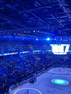 an ice hockey arena filled with lots of people watching the game in blue lighting up