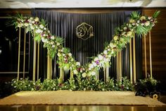 a wedding stage with flowers and greenery on the front, along with a monogrammed backdrop