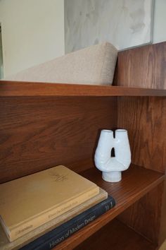 a book shelf with two books and a vase on it