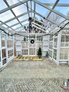 the inside of an old greenhouse with brick flooring and glass walls on both sides