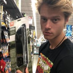 a young man holding up a skateboard in a store