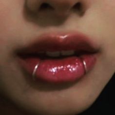 a woman's lips are covered with shiny lipstick and the lip ring is clearly visible