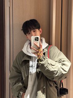 a young man taking a selfie in front of a door with his cell phone