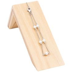 a pair of white pearls hanging from a wooden display stand on top of a piece of wood