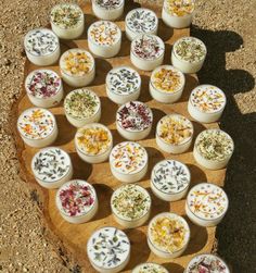 an assortment of small containers with flowers on them sitting on top of a wooden board