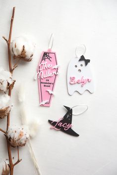 three tags are laying on top of cotton and one has a black cat, the other is pink