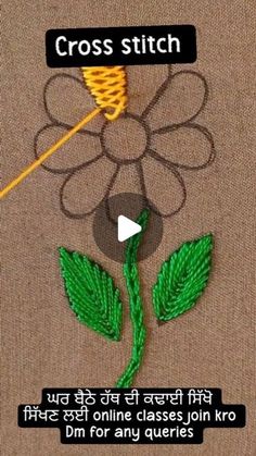 the video shows how to make a cross stitch flower with green leaves and thread on it