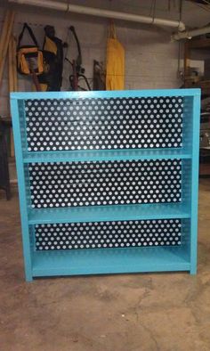 a blue bookcase with white polka dots on the front and bottom shelves, sitting in a garage