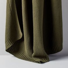 an olive green knitted blanket draped over a white surface