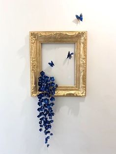 there is a frame with blue flowers in it and butterflies on the wall next to it