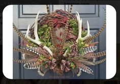 a wreath with deer antlers and plants on it