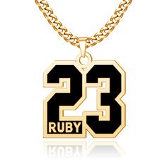 a gold necklace with the number 23 on it and a black pendant attached to it