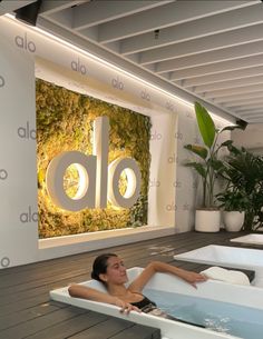 a woman laying in a bathtub with moss growing on the wall behind it and an alcove