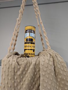 a can sitting on top of a blanket in the shape of a purse with handles