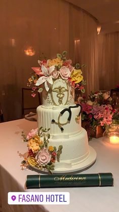 a white wedding cake with flowers and glasses on top is sitting on a table in front of candles