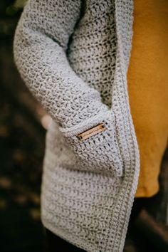 a woman wearing a gray crochet cardigan sweater