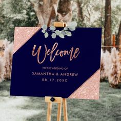 an easel with a welcome sign on it in front of some grass and trees