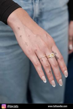 a woman's hand with stars on it and a ring in her left hand