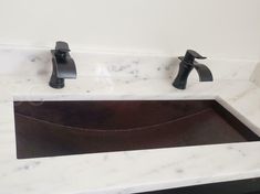 a bathroom sink with two faucets and marble counter top