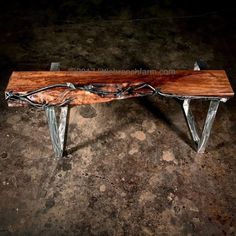 a wooden bench sitting on top of a cement floor next to a metal frame and wood slab