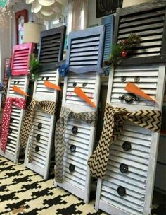 several wooden shutters decorated with ribbons and bows are lined up on the floor in front of a window