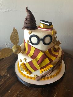 a harry potter themed birthday cake with glasses and wands on top, sitting on a wooden table