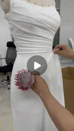 a woman in a white dress is working on a piece of clothing that has been sewn