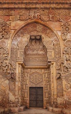 an intricately carved doorway in the middle of a stone wall with carvings on it