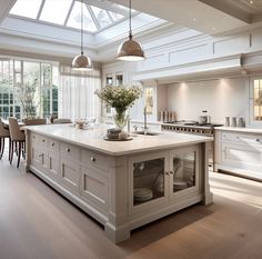 a large kitchen with an island in the middle and two pendant lights hanging from the ceiling