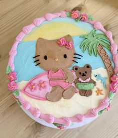 a hello kitty cake with a teddy bear on the front and palm tree in the back