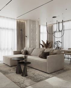 a living room filled with furniture next to tall windows and drapes on the wall