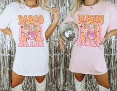 two women in matching disco t - shirts posing for the camera with a disco ball