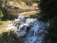 a small waterfall in the middle of a forest with lots of water running down it