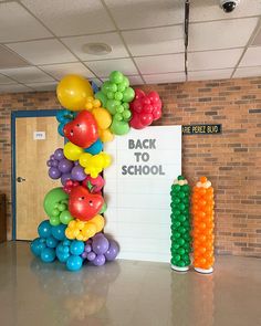 there are many balloons on the wall in front of this back to school sign that says back to school