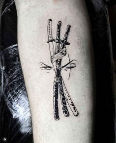 a black and white photo of a tattoo with two knives tied to each other on someone's arm