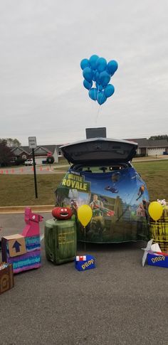 the back of a car with balloons attached to it's trunk in front of a parking lot