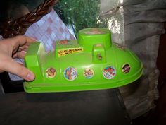 a child's green toy boat sitting on top of a black table next to a person