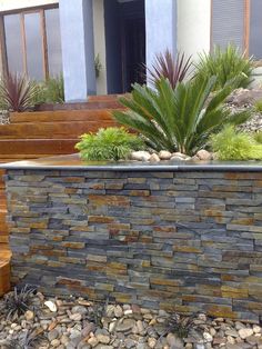 a stone wall next to some steps and plants