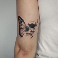 a skull with a butterfly on it's arm is shown in black and white