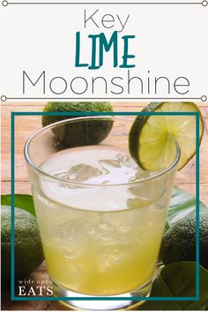 a glass filled with lemonade sitting on top of a table next to an avocado