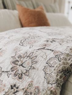 a bed with a floral comforter and pillows