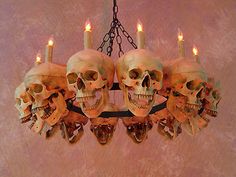 a chandelier with skulls hanging from it's sides and lit candles in the middle