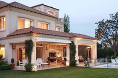 a house with an outdoor living area and pool in the front yard at night time