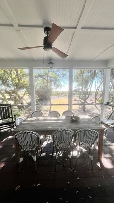 a table and chairs on a porch with a ceiling fan in the middle of it