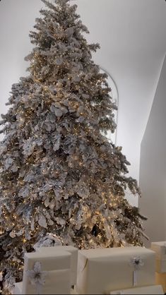 a white christmas tree with presents under it