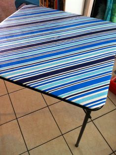 a blue and white striped table cloth sitting on top of a tile floor next to a red box