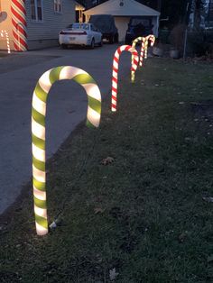 some candy canes are lined up on the side of the road in front of a house