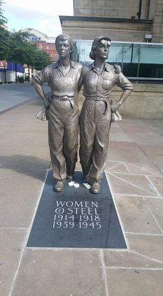 two statues of women standing next to each other in front of a sign that says women outside