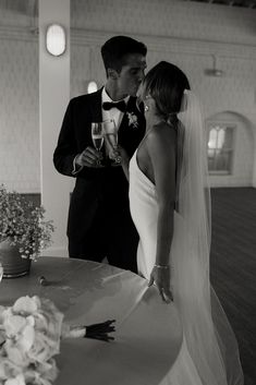 a bride and groom kissing in front of a table with flowers on it at their wedding reception