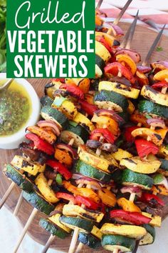 grilled vegetable skewers on a plate with dipping sauce